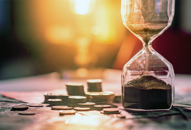 photo: hourglass on table with banknotes and coins (iStockphoto)