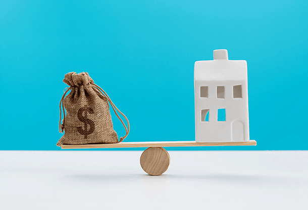 image: money bag and small apartment building on basic balance (iStockphoto)